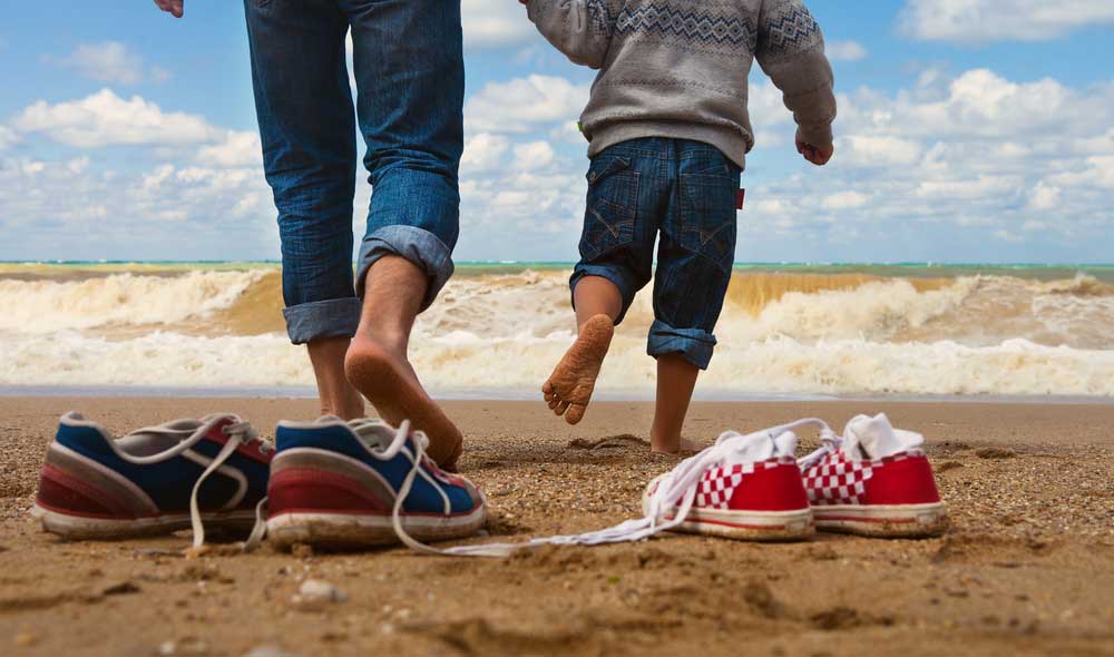 PIeds d'enfants et d'un père sur la plage en train de courir